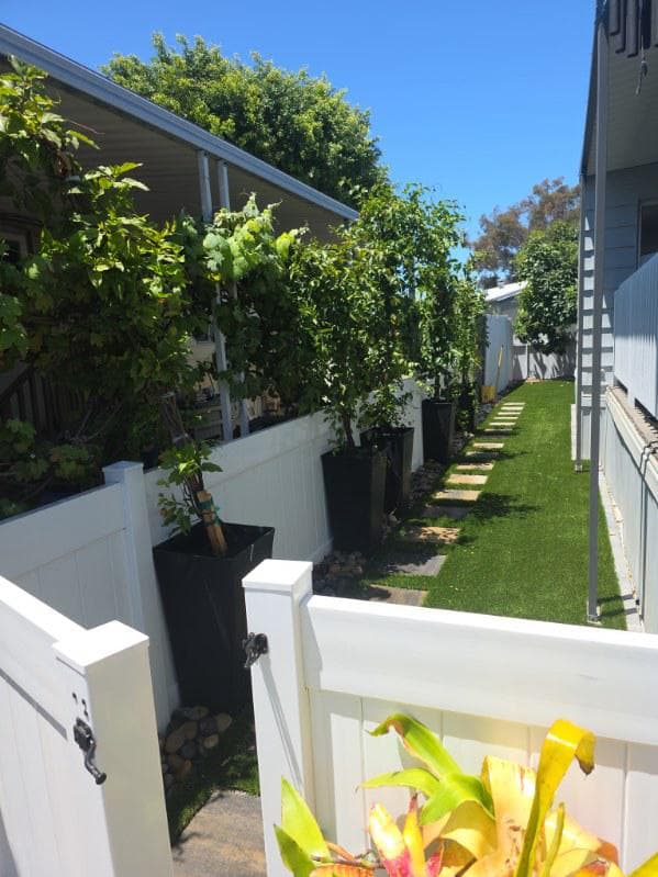 picture of newly remodeled residential walkway with custom pavers turf and white fence